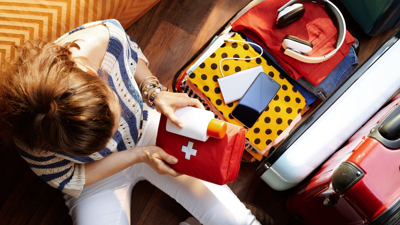 Woman packing first aid kit into suitcase pharmacy-trip-iStock-1155566546.jpg