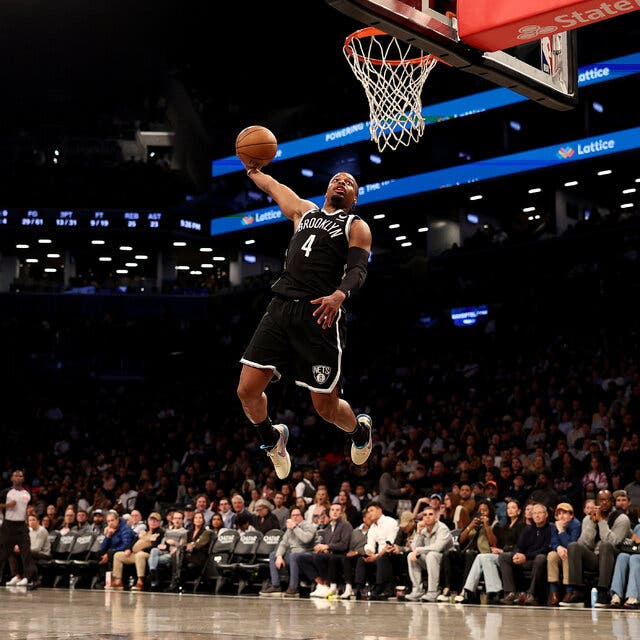 A leaping player for the Brooklyn Nets about to dunk a basketball with no defender near him during an N.B.A. game. 