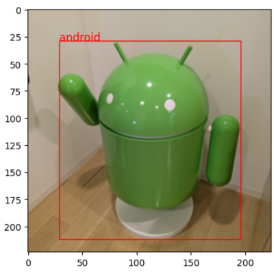 Result in PaliGemma 2 Mix: A large, green Android figure stands on a white platform, enclosed by a red box. The word "android" is written in red above the figure.