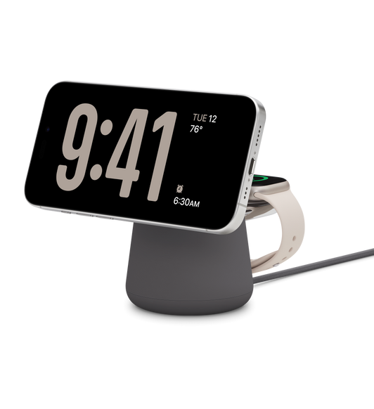 Station de charge sans fil 2-en-1 BOOST CHARGE PRO de Belkin avec MagSafe, un iPhone chargeant en mode paysage, une Apple Watch en charge également juste derrière, un câble de charge USB-C en bas.