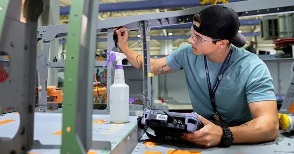 male employee wearing safety goggles and handling an electronic device