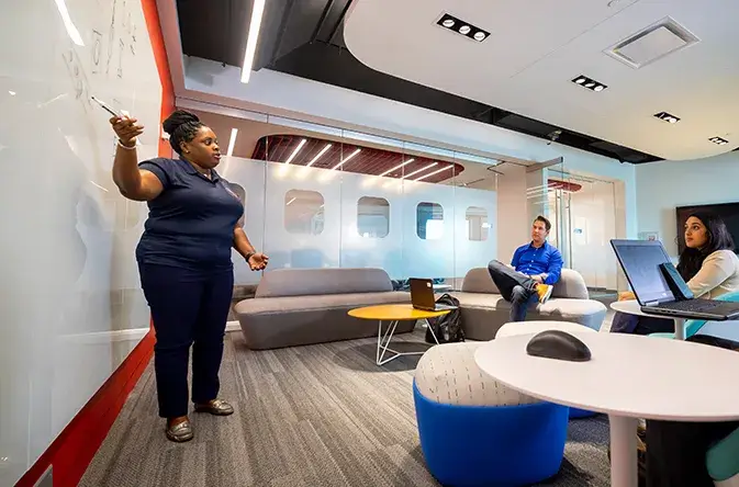 black female employee conducting a whiteboard presentation in an employee meeting room