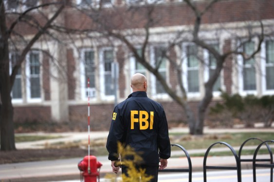 a photo of an FBI agent standing with his back from the camera, showing the yellow letters FBI on his jacket