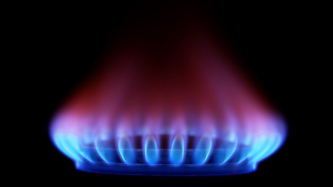 A blue flame of burning methane emanates from a burner.