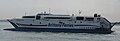 photo d’un ferry vu de côté, la proue à gauche et la poupe à droite. Le bateau est principalement blanc, avec le texte "Britanny Ferries" en grandes lettres bleues au milieu de la coque, ainsi que deux lignes bleues et rouges horizontales.