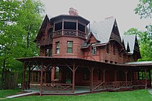 grande maison rouge en haut d'une colline, tour octogonale, parc arboré