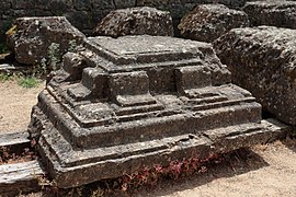 Photo d'une pierre d'angle sculptée posée au sol.