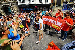 A young man speaking to an applauding crowd