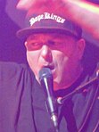 DJ Lethal singing at a concert with his arms raised.