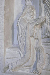 Tympanon zobrazuje klečící ženu v jeptišském oděvu.