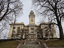 Large government building with trees in front, seen from the bottom of steps