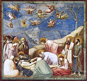 Square fresco. In a shallow space like a stage set, lifelike figures gather around the dead body of Jesus. All are mourning. Mary Magdalene weeps over his feet. A male disciple throws out his arms in despair. Joseph of Arimethea holds the shroud. In Heaven, small angels are shrieking and tearing their hair.