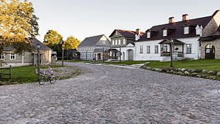 Photographie de maisons en pierre avec une rue pavée.