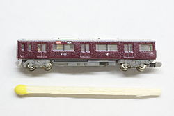 Modelo do vagão Hankyu 9000 na escala T com um palito de fósforo para comparar o tamanho.