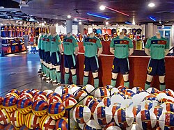 A number of jerseys, footballs and other association football equipment inside FC Barcelona's sports store.