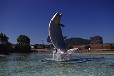 Escultura de salmão no centro de Campbellton, o edifício do centro da cidade e o Montanha de Sugarloaf ao fundo.