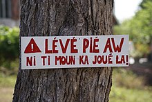 Panneau en créole de Guadeloupe signifiant : « Ralentissez, nos enfants jouent ici » et plus littéralement : « Lève ton pied (de l'accélérateur), il y a des enfants qui jouent là ».