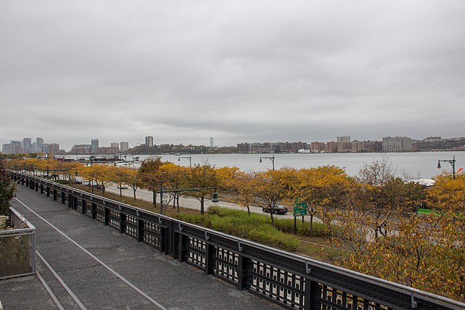 ... a view from the former High Line in New York City, down to the bank of Hudson river with trees at a street.