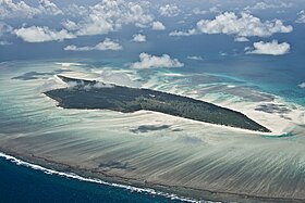 Vue aérienne de l'île Juan de Nova avec la barrière et les récifs coralliens qui l'entourent.