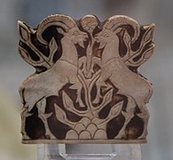 Placa d'incrustació de nacre gravada, que representa dos cabraços dempeus sobre les potes posteriors al voltant d'un arbust.