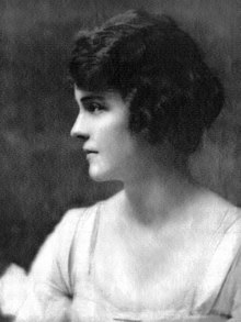 A black-and-white photograph of Ginevra King captured in profile, looking to the left. She has short, wavy hair styled close to her head and is wearing a light-colored dress.