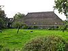 Kop-hals-rompboerderij met onderkelderd woonhuis met zesruitsvensters en met bedrijfsruimte aan de zijde van de stal