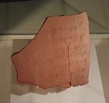 Fragment de poterie portant une inscription peinte à demi effacée.