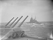 Black and white photograph of a warship in rough seas