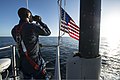 A Sonar Technician stands lookout in the sail aboard Minnesota as the boat transits Port Canaveral, FL.