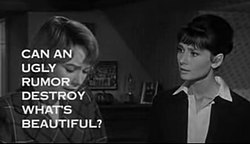 Still shot of a film trailer showing Shirley MacLaine looking down at the left and Audrey Hepburn to her right staring at her, in a bedroom. The words "Can an ugly rumor destroy what's beautiful?" obscure much of MacLaine's face