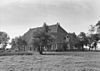 Boerderij met ingebouwd zeer breed dwarshuis met zesruitsvensters onder schilddak met dakkapel en schoorstenen