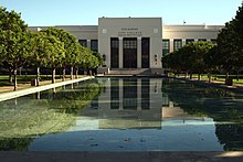 Photographie couleur de la façade du Pasadena City College, en pierre blanche. Au premier plan, un grand bassin rectangulaire bordé d'arbres