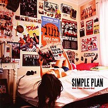 A photo of a woman looking at magazines with several pictures of Simple Plan on the wall