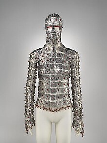 A garment made of plates of metal joined together, adorned with small red gemstones. It covers the entire torso, arms, and face, except for the eyes.