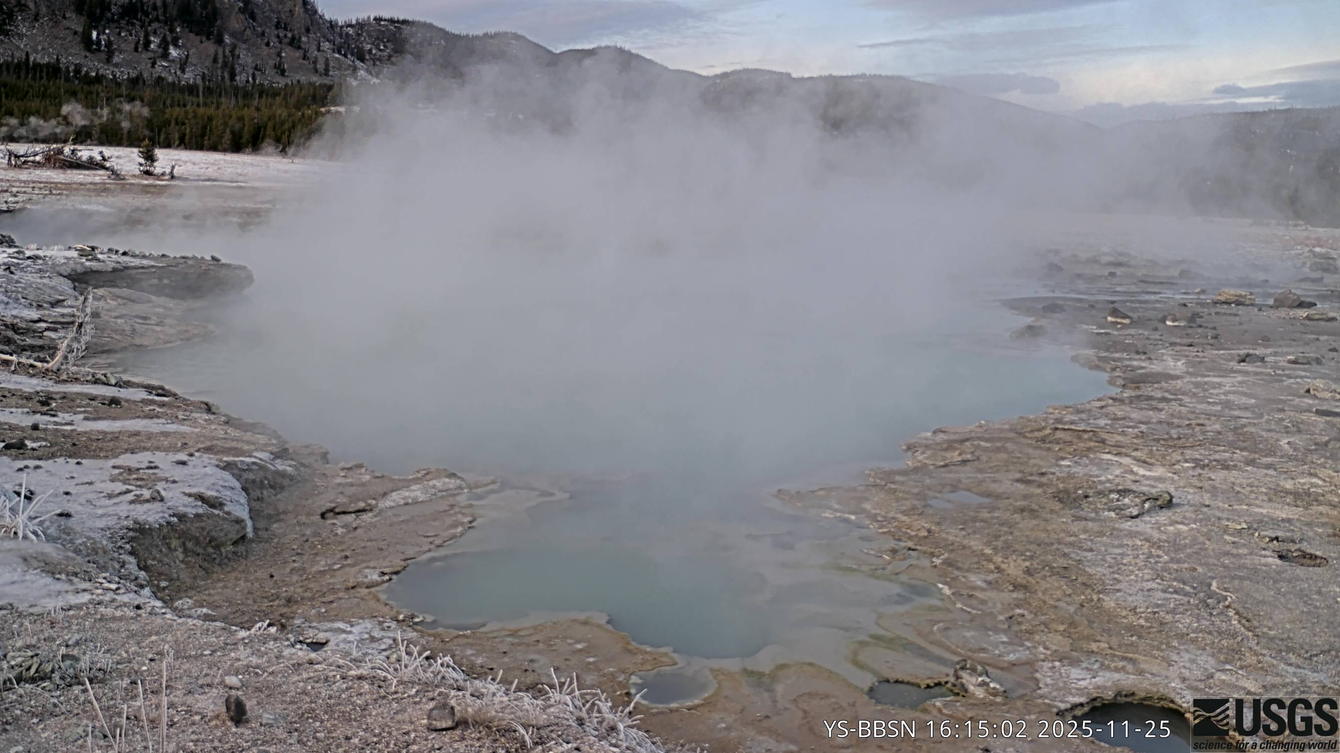 Looking at hot spring with high cliffs in the background