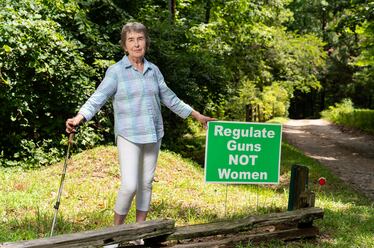 Mary Ellen Myers, a member of the Banks County Democratic Committee, poses with a sign she used to display in her yard in Alto. Myers said she found trash, such as drink cans, thrown at the sign, although she's faced little other backlash. “There’s some civility in this county,” said Myers, who has lived in Banks County for more than two decades. (Seeger Gray / AJC)