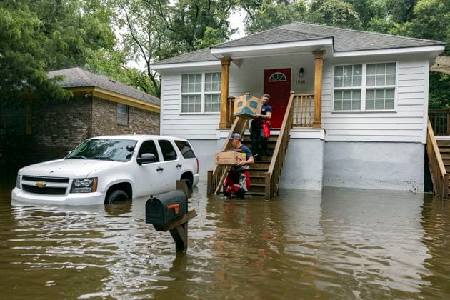 Savannah Fire Advanced Firefighters Ron Strauss, top, and Andrew Stevenson, below, carry food to residents in the Tremont Park neighborhood that where stranded in stormwater from Tropical Storm Debby, Tuesday, Aug. 6, 2024, in Savannah, Ga. (AP Photo/Stephen B. Morton)