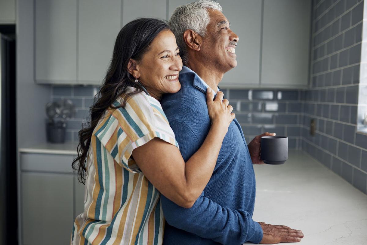 Smiling couple in a kitchen looking out the window