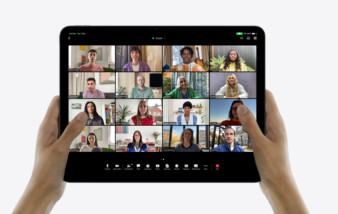 A pair of hands holding an iPad Pro showcasing a group FaceTime call.