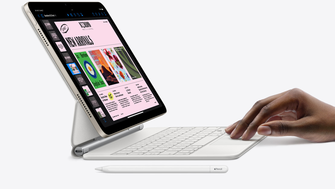 Skats no sāna uz iPad Air, kurā atvērta Keynote aplikācija un kam pievienota Magic Keyboard; uz skārienpaliktņa ir roka, bet blakus ir Apple Pencil.
