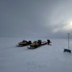 A group of people riding skis across snow covered ground