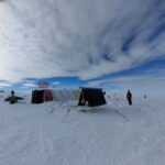 Ice covered ground with a cloudy sky above.