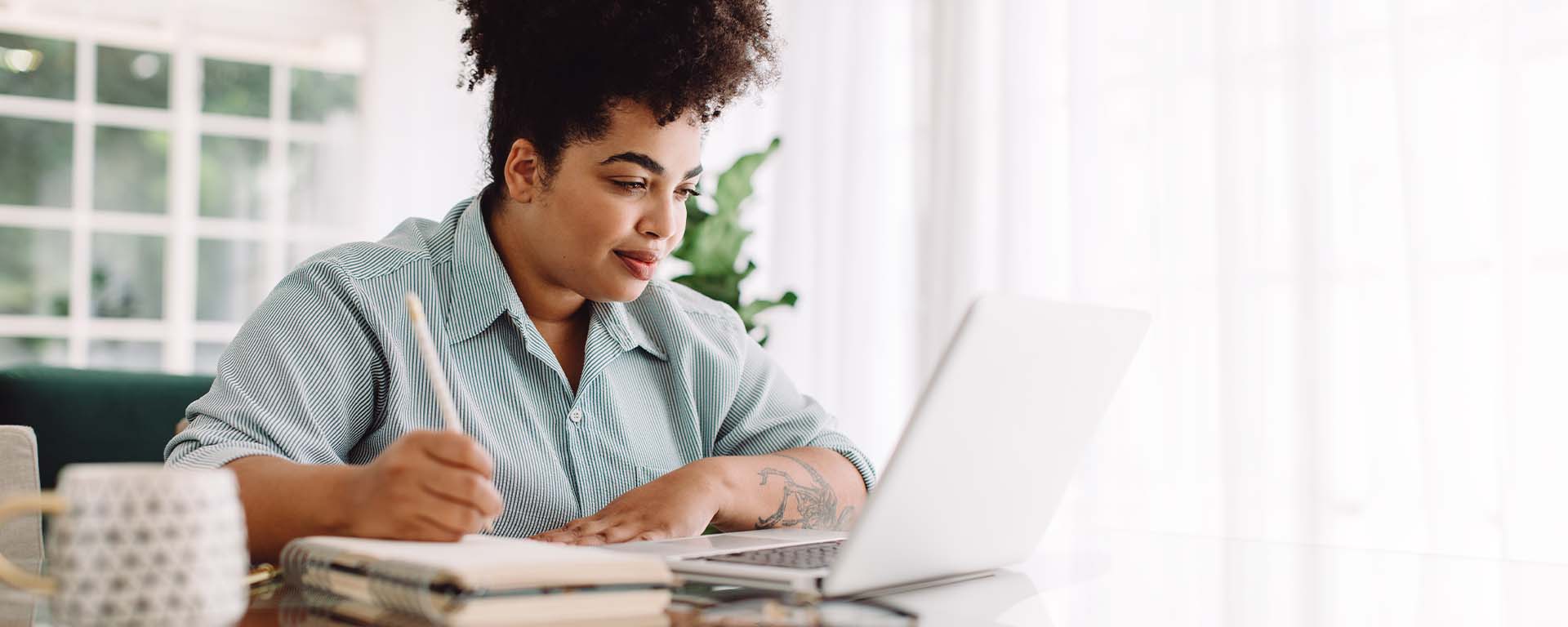 A person smiles while looking at a laptop