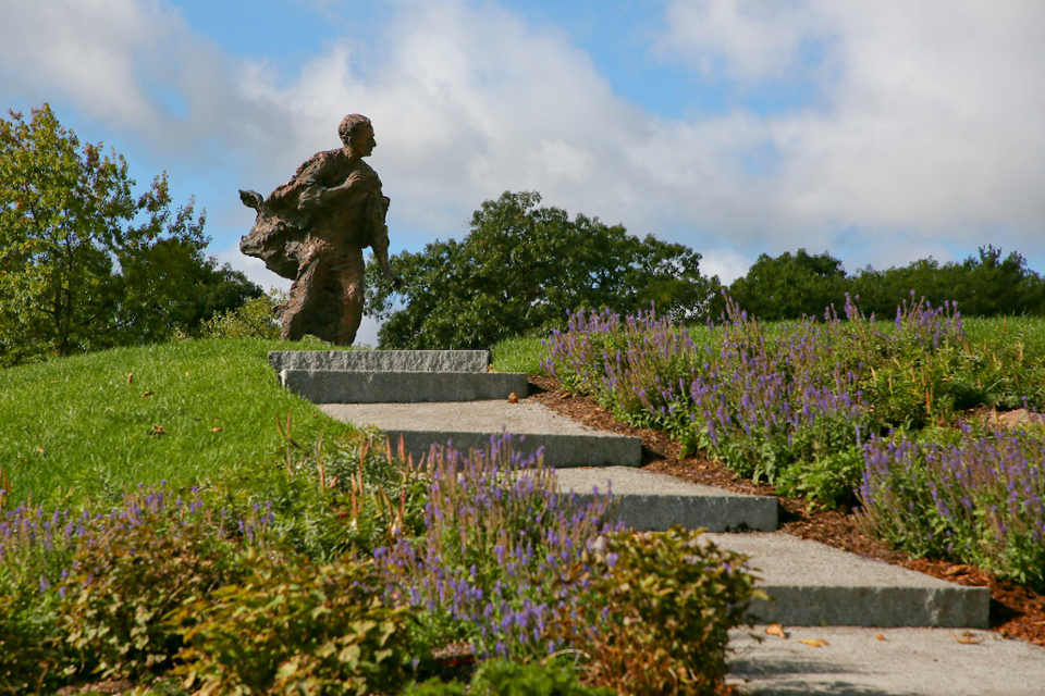 Statue of Louis Brandeis at the top of a flight of stone steps, surrounded by grass