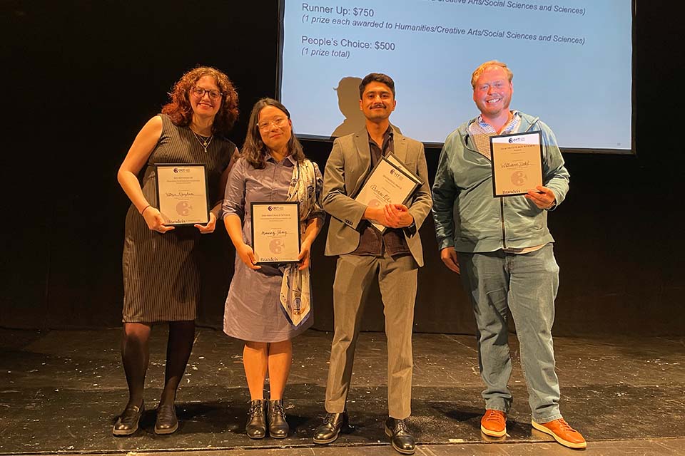 Three Minute Thesis winners Victoria Khaghani, Manning Zhang, Pranav Ojha, and Will Dahl pose with their certificates on stage.