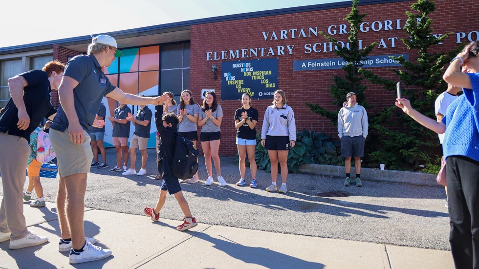 Kids walk into school surrounded by Brown student-athletes cheering them on