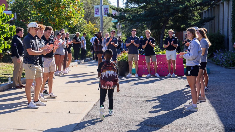 Kids walk into school surrounded by Brown student-athletes cheering them on