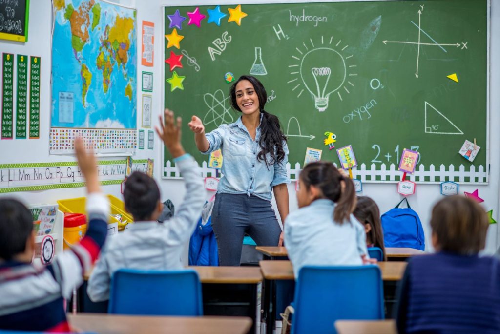 teacher leading elementary class in front of blackboard