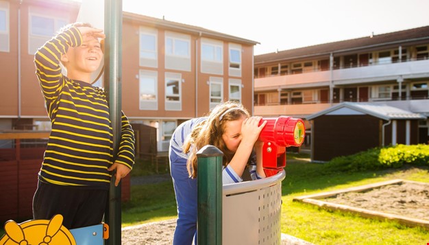 2 barn som leker på lekeplass utenfor leiligheter