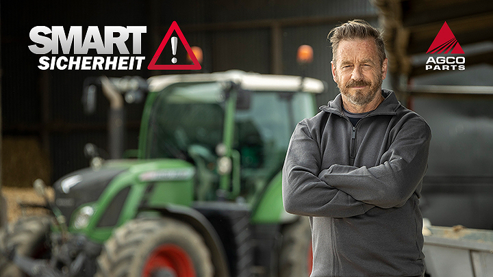 Ein Landwirt steht mit verschrenkten Armen rechts vor einem Fendt Traktor.